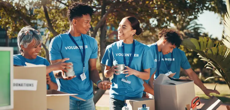 Smiling volunteers in blue “Volunteer” T-shirts working together outdoors