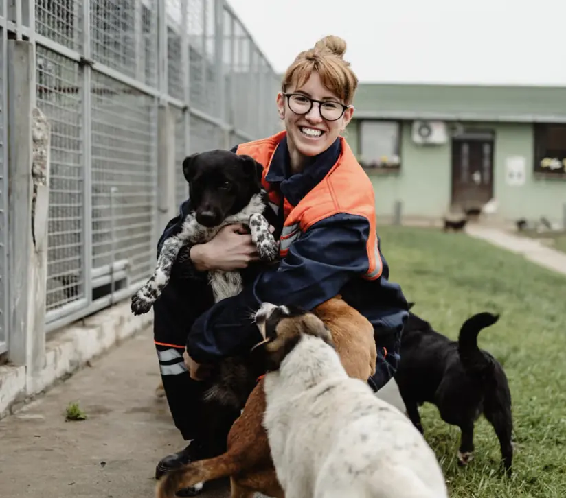 Smiling animal-shelter volunteer hugging rescued dogs